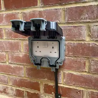 Outdoor double socket fitted on a brick wall