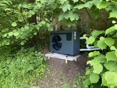 Pool heat pump on a base among garden plants